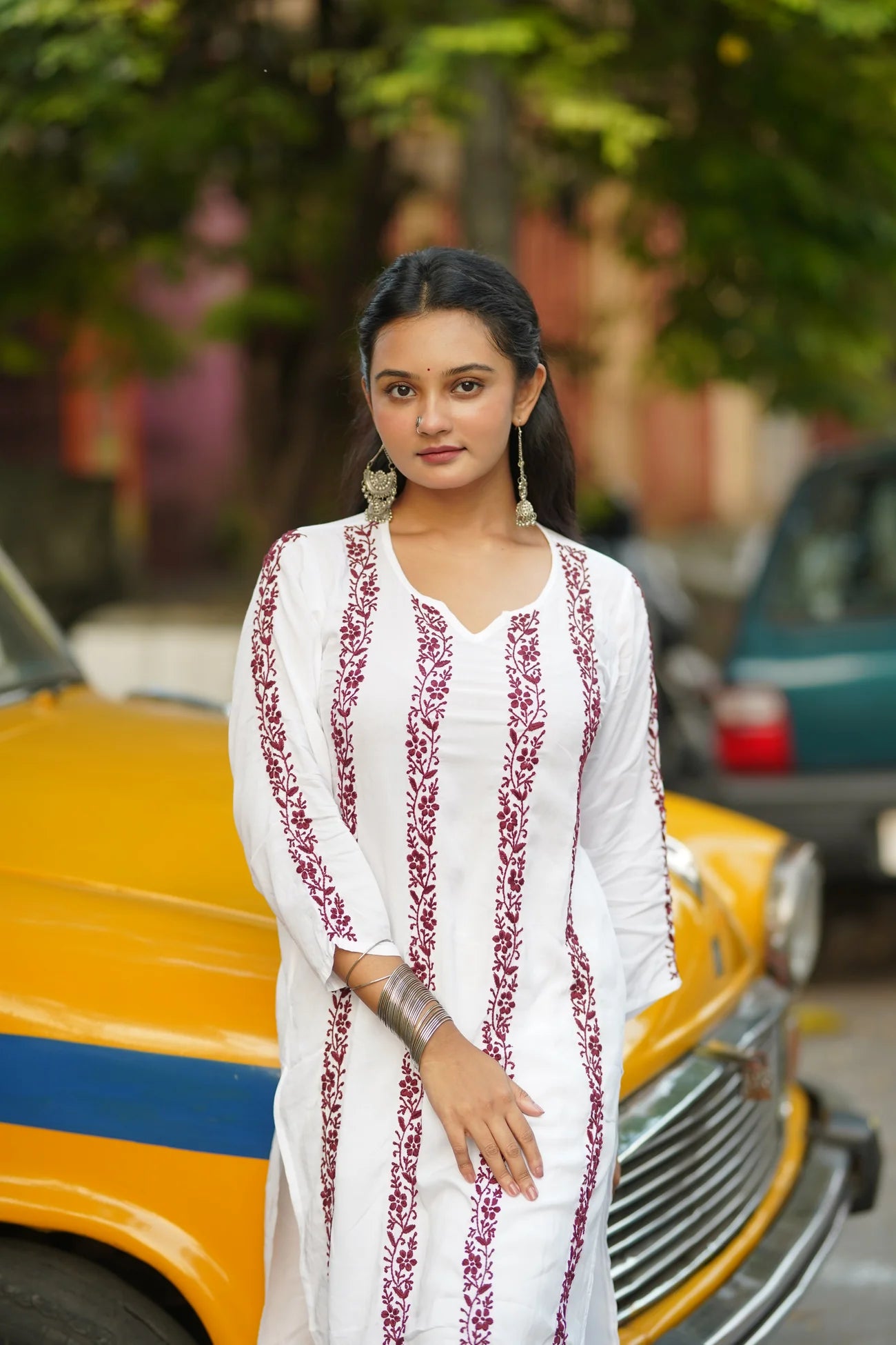 Woman wearing a white embroidered top with red patterns.