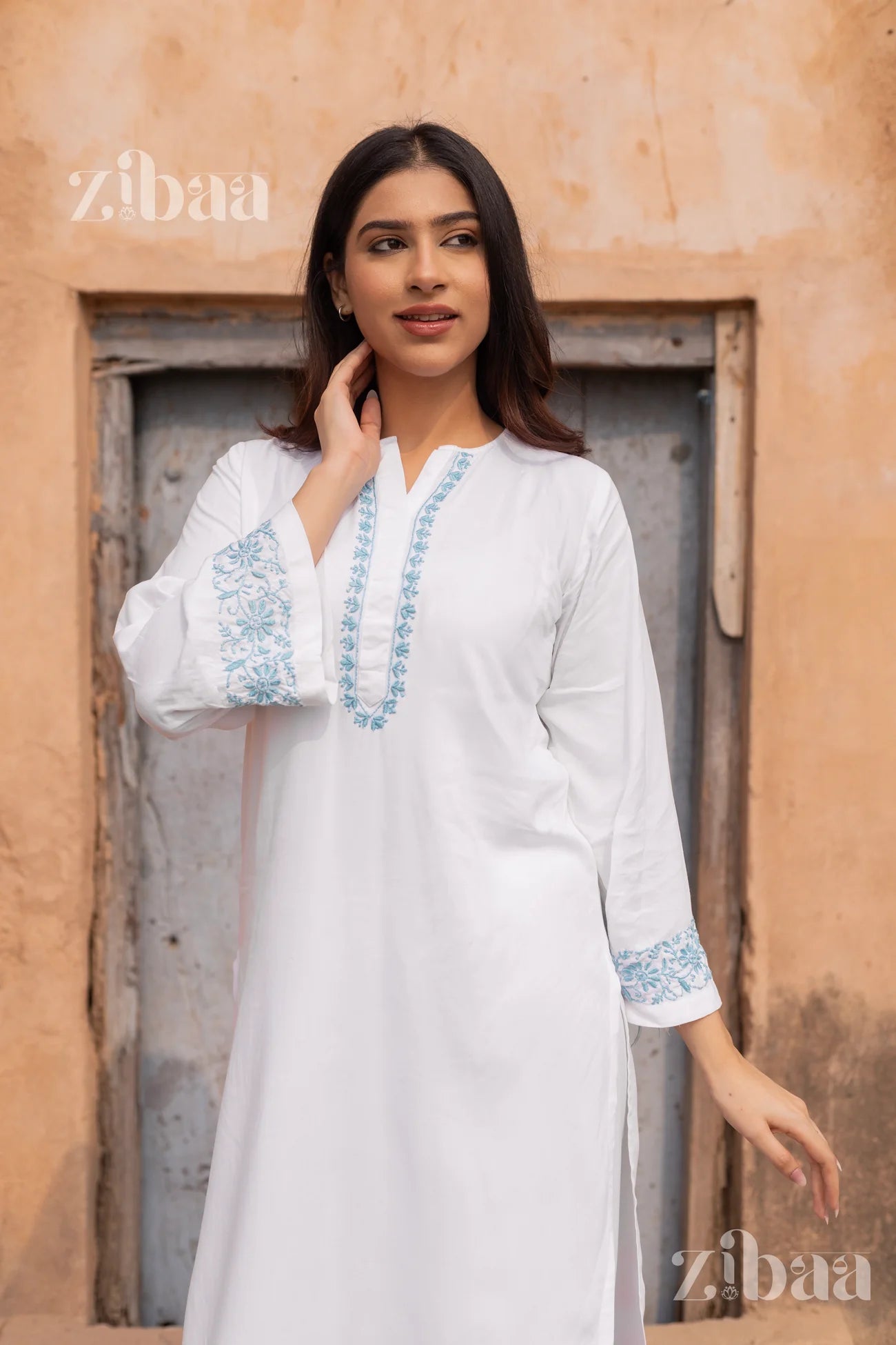 White garment with blue embroidery being worn by a person, brand 'zibaa' visible.